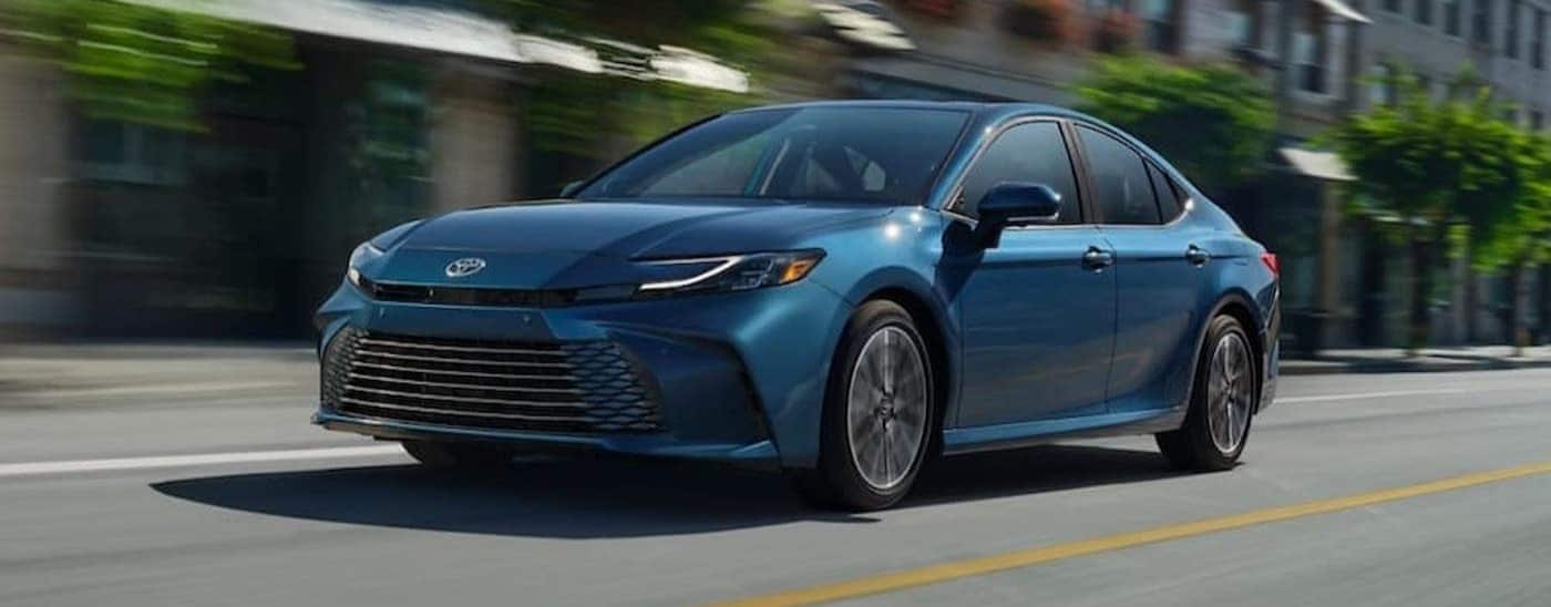 A blue 2025 Toyota Camry XLE driving to view a used Toyota for sale near Clarksville.
