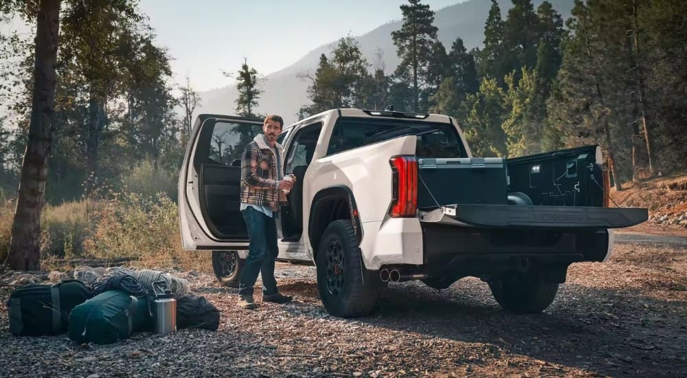 A man unloading camping gear from the bed of his white 2024 Toyota Tundra TRD Pro.