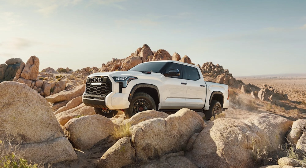 A white 2024 Toyota Tundra TRD Pro off-roading over boulders.