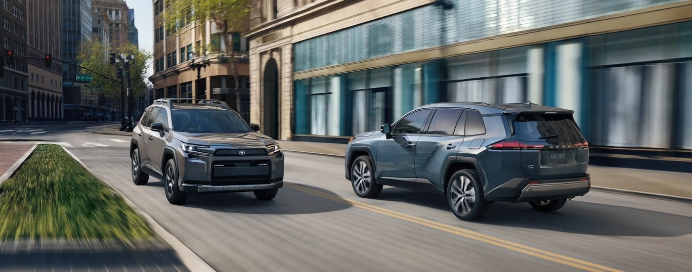 A grey and a blue 2026 Toyota RAV4 driving past each other.