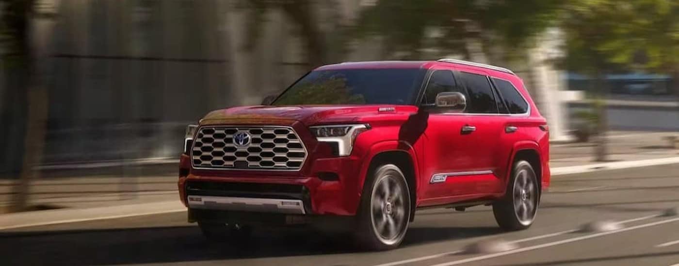 A red 2023 Toyota Sequoia driving on a highway.