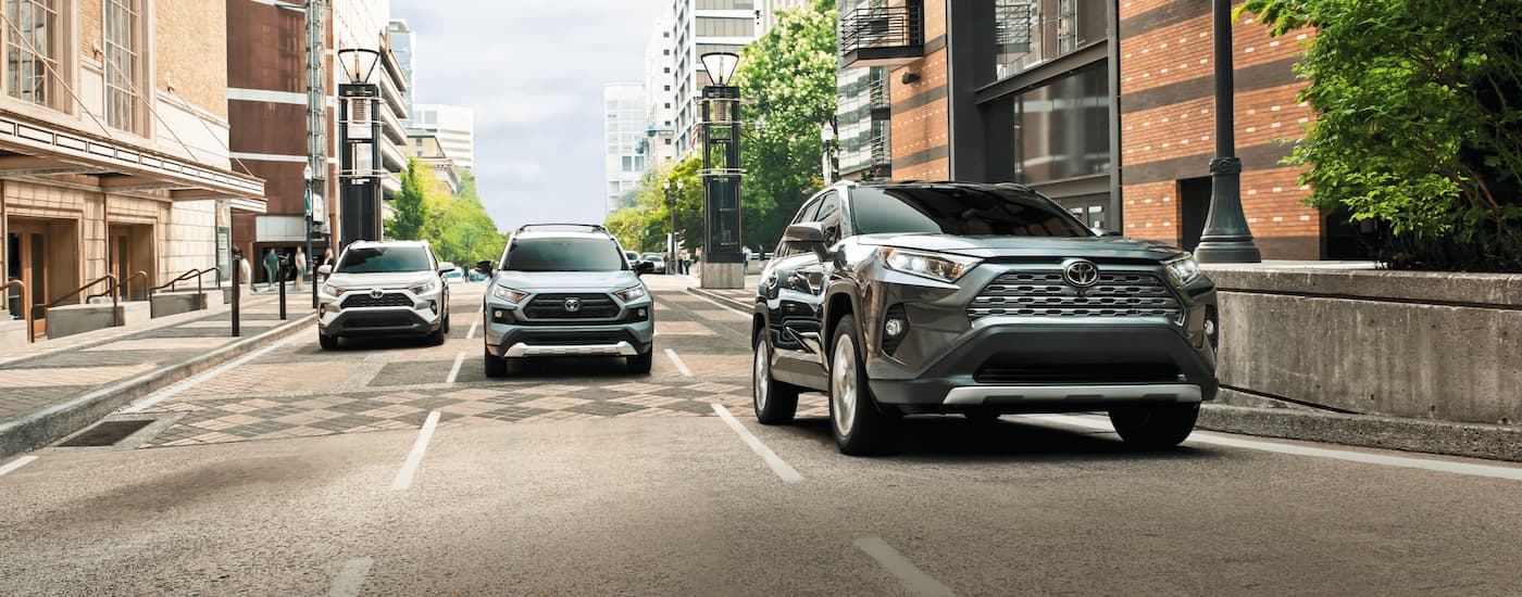 Grey 2021 Toyota RAV4 driving through a city with two more behind it