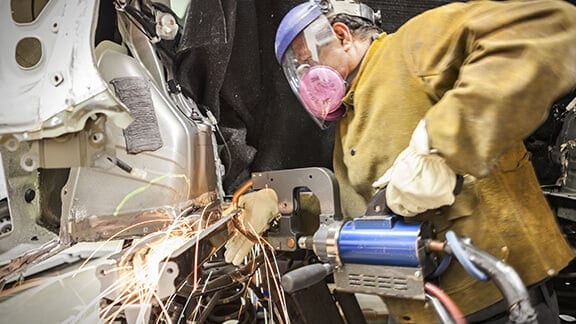 Toyota Collision Center Technician testing engine and recording results on clipboard.