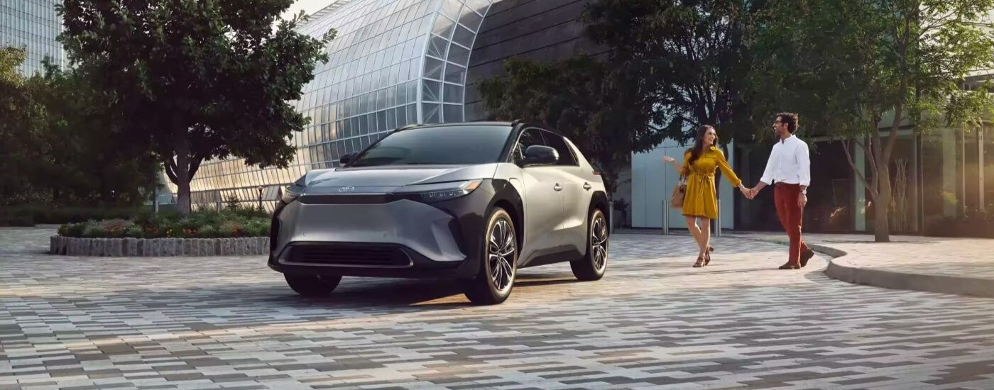 A grey 2023 Toyota bZ4X Limited is shown near a couple.