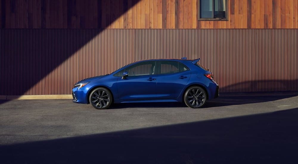 A blue 2024 Toyota Corolla Hatchback is shown parked near a building.