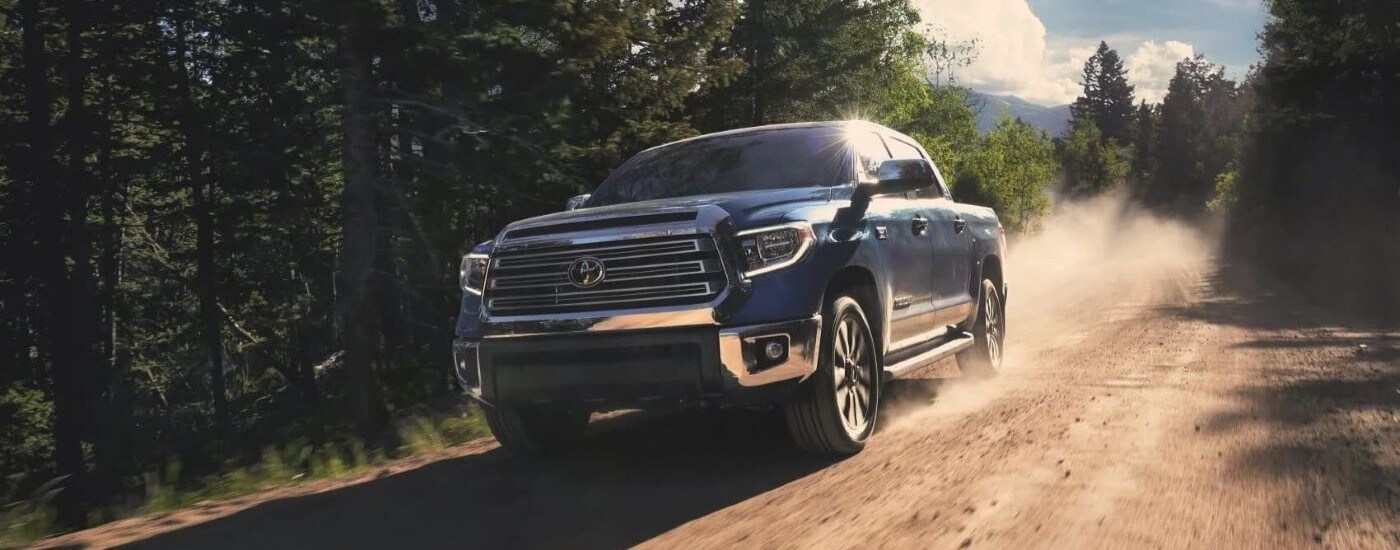 A blue 2020 Toyota Tundra is shown driving on a dirt road.