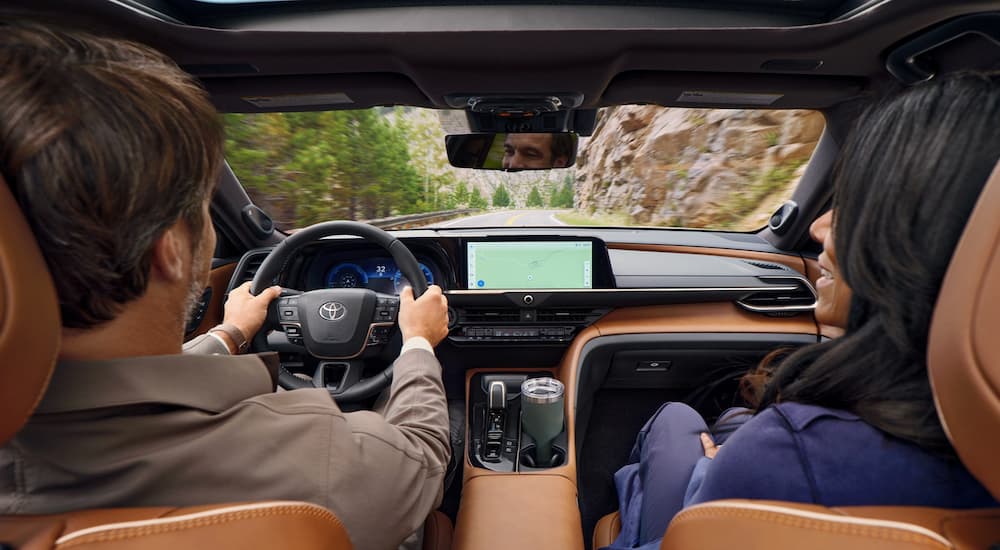 Two people are shown in the black and tan interior of a 2025 Toyota Crown Signia.