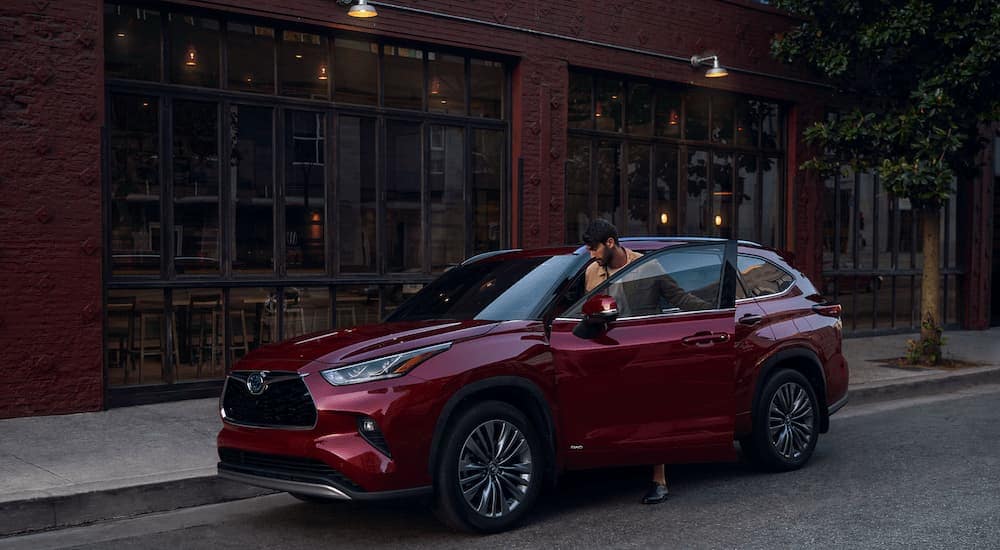 A person is shown getting into the driver's seat of a red 2023 Toyota Highlander.