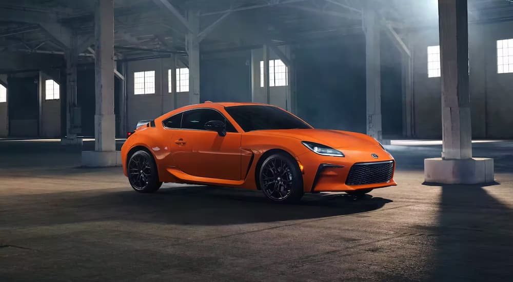 An orange 2023 Toyota GR86 is shown parked in a warehouse after leaving a Toyota dealer.