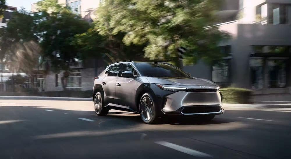 A silver 2023 Toyota BZ4X is shown driving on a city street.