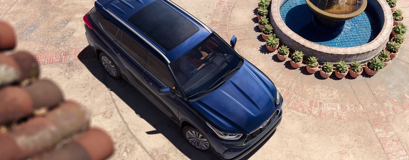 A blue 2023 Toyota Highlander Hybrid for sale is shown from above on a brick driveway.