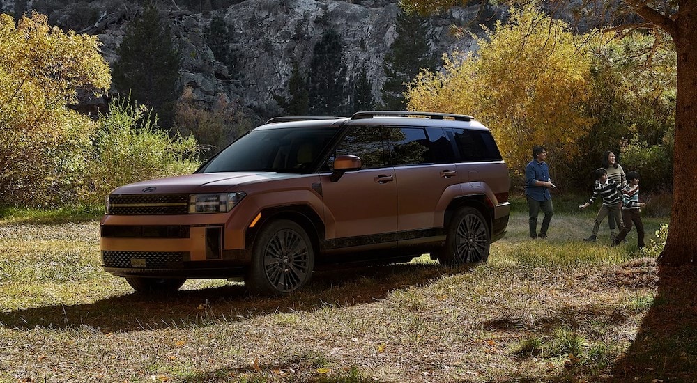 A copper 2024 Hyundai Santa Fe Hybrid is shown parked near a family.