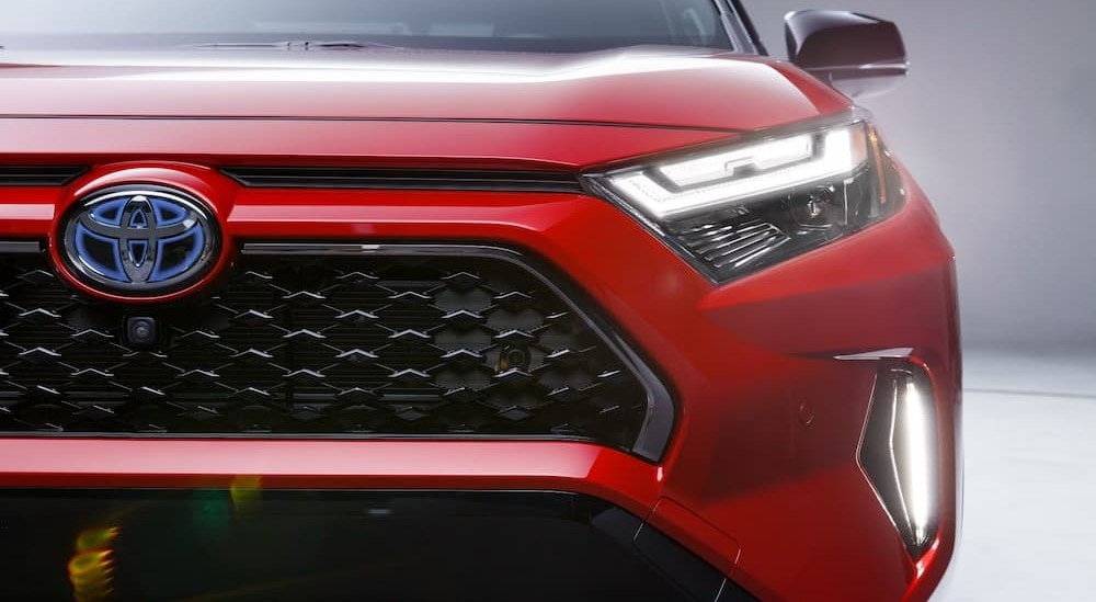 A close-up of the grille and headlight on a red 2024 Toyota RAV4 Prime is shown.