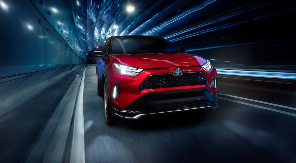 A red 2024 Toyota RAV4 Prime XSE driving through a tunnel with blue lights.