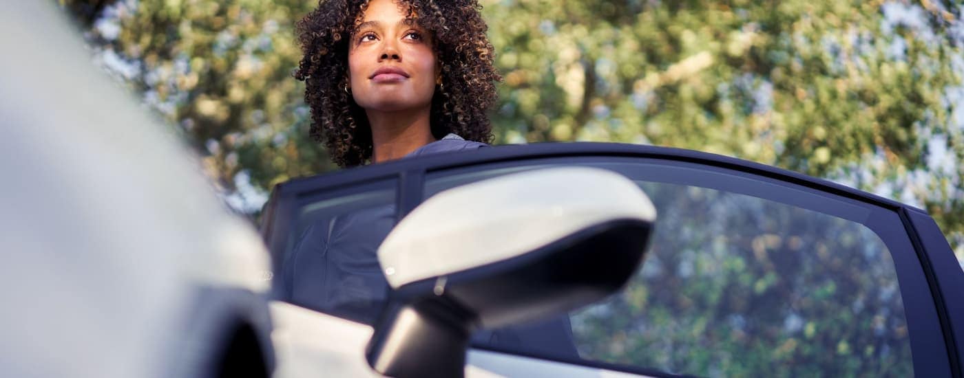 A woman is getting into the driver's side of a white 2024 Toyota Corolla LE.