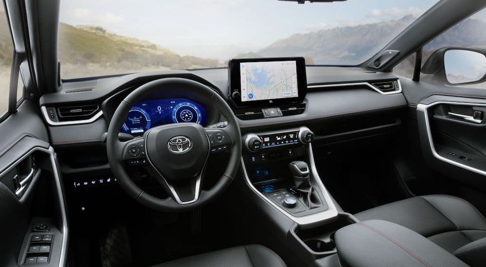 The black interior of a 2023 Toyota RAV4 is shown from the driver's seat.