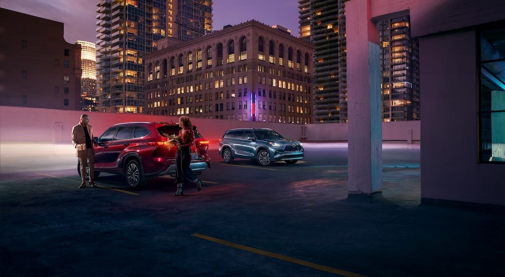 2024%20Toyota%20Highlander%20Hybrid%20-%20Two.jpg A red and a silver 2024 Toyota Highlander Hybrid are shown parked near city buildings.
