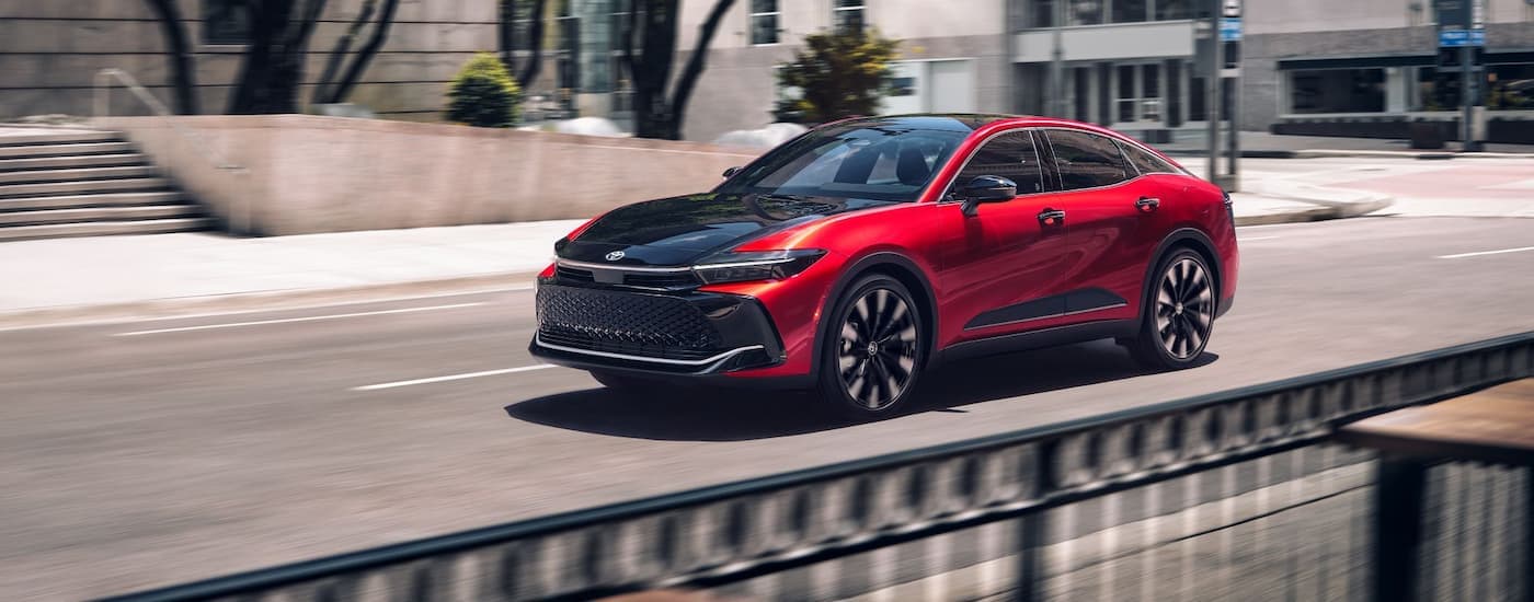 A red and black 2024 Toyota Crown Platinum is driving on a city street to a Toyota dealer near Brooklyn.