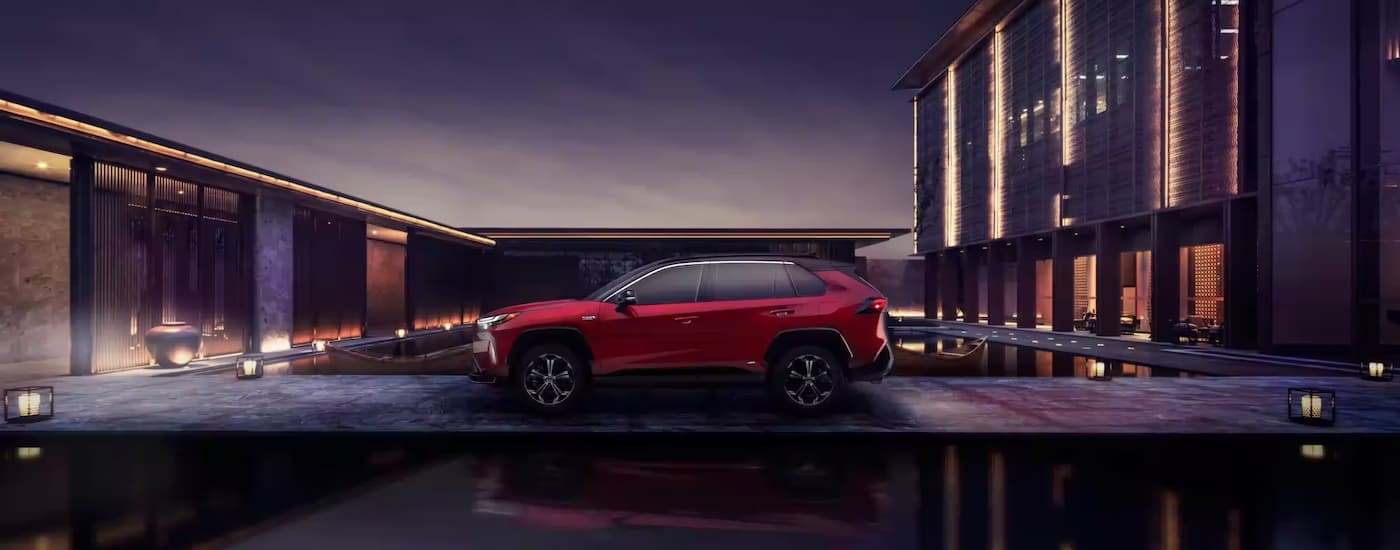 A red 2023 Toyota RAV4 Prime is shown from the side in a city at night.