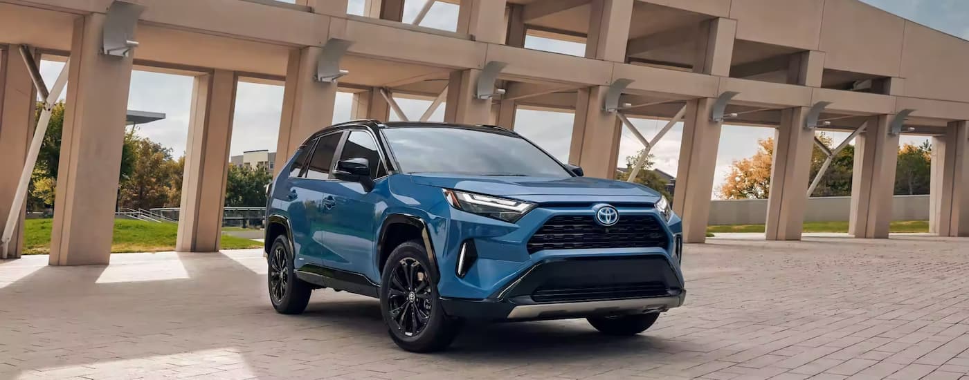 A blue 2023 Toyota RAV4 XSE Hybrid is shown parked next to a walking bridge.