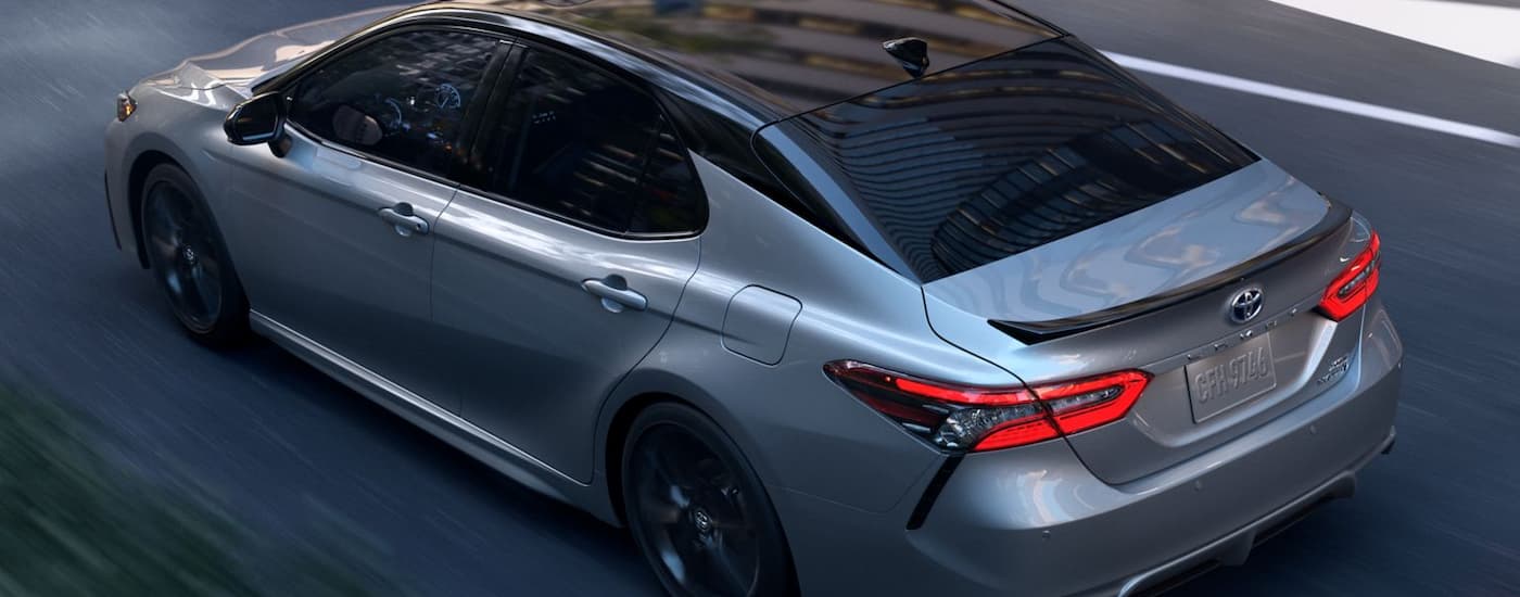 A silver 2024 Toyota Camry XSE Hybrid is shown from a rear angle while parked.