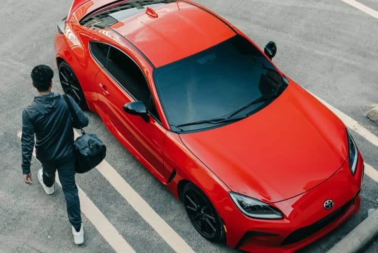 Person walking up to red car.