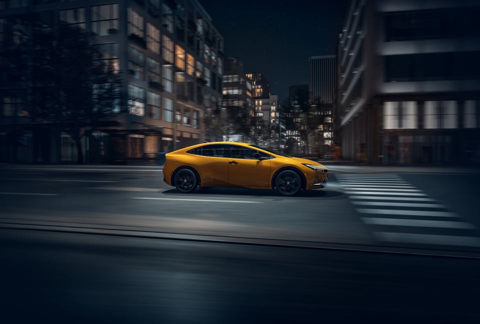 Yellow Prius driving in city at night