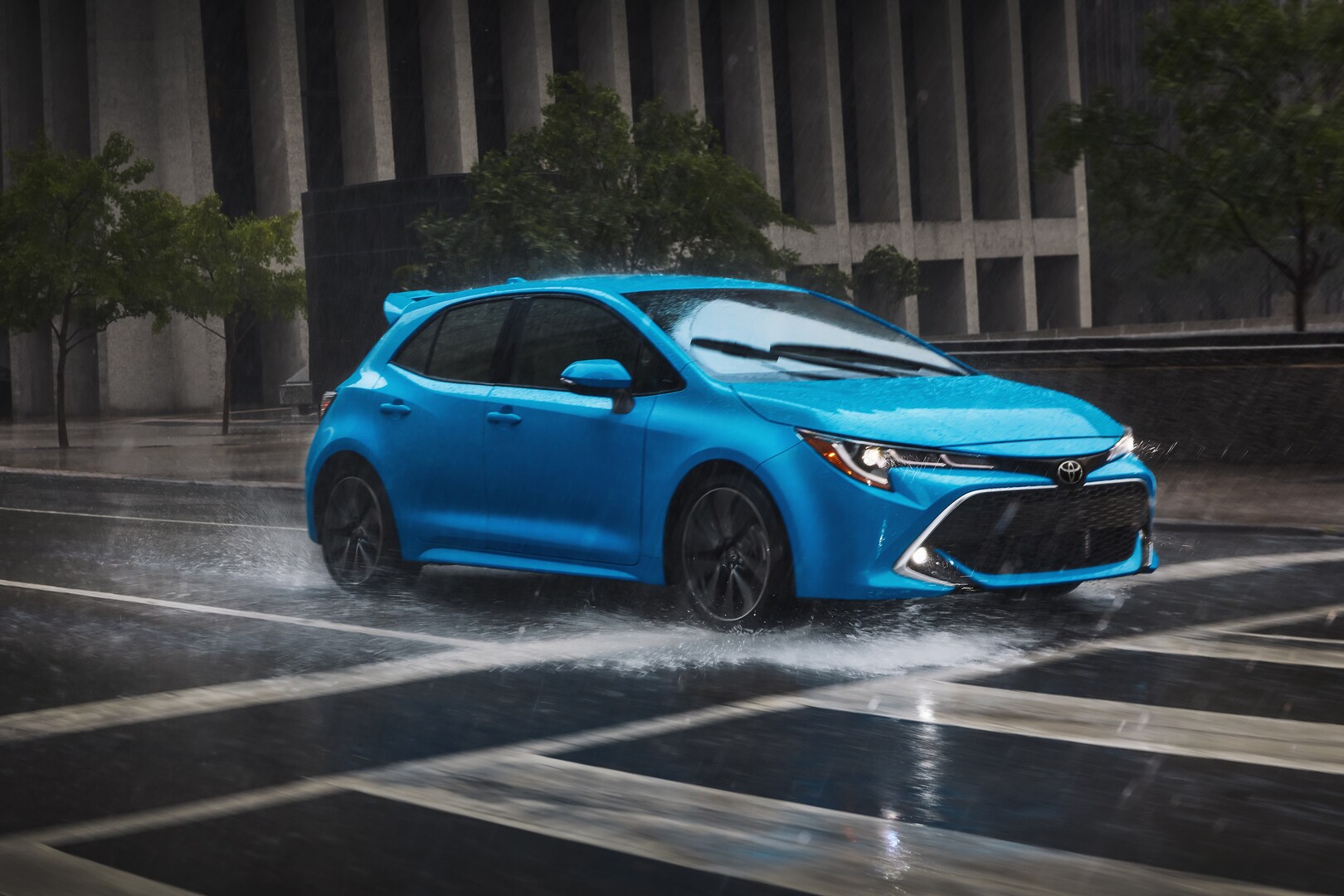 Blue Toyota Corolla Hatchback driving in the rain