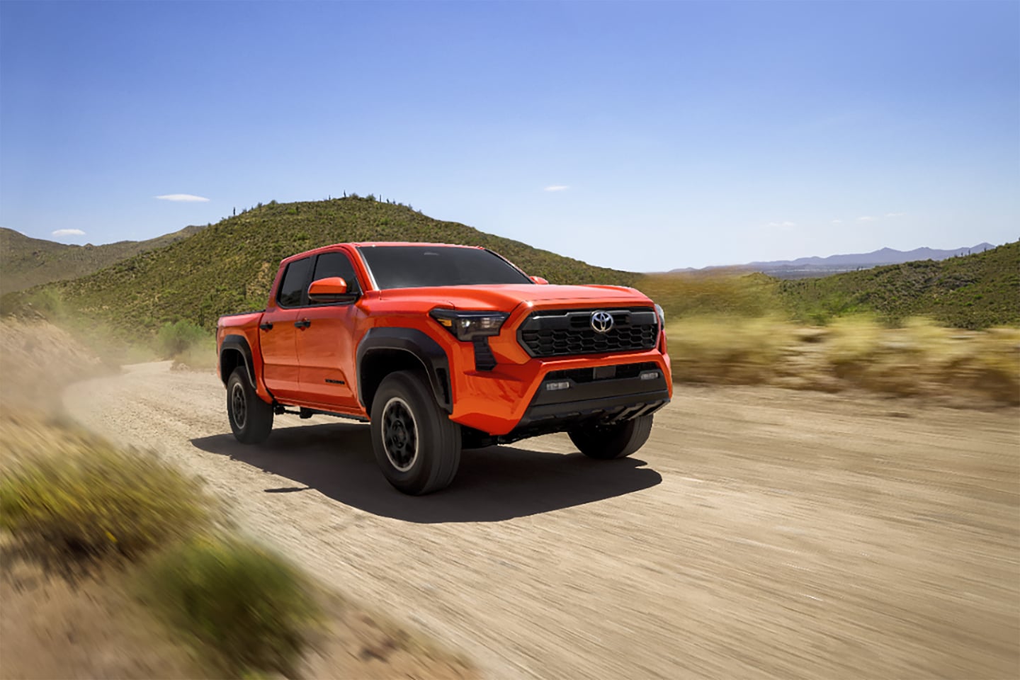 OrangeToyota Tacoma driving on dirt road