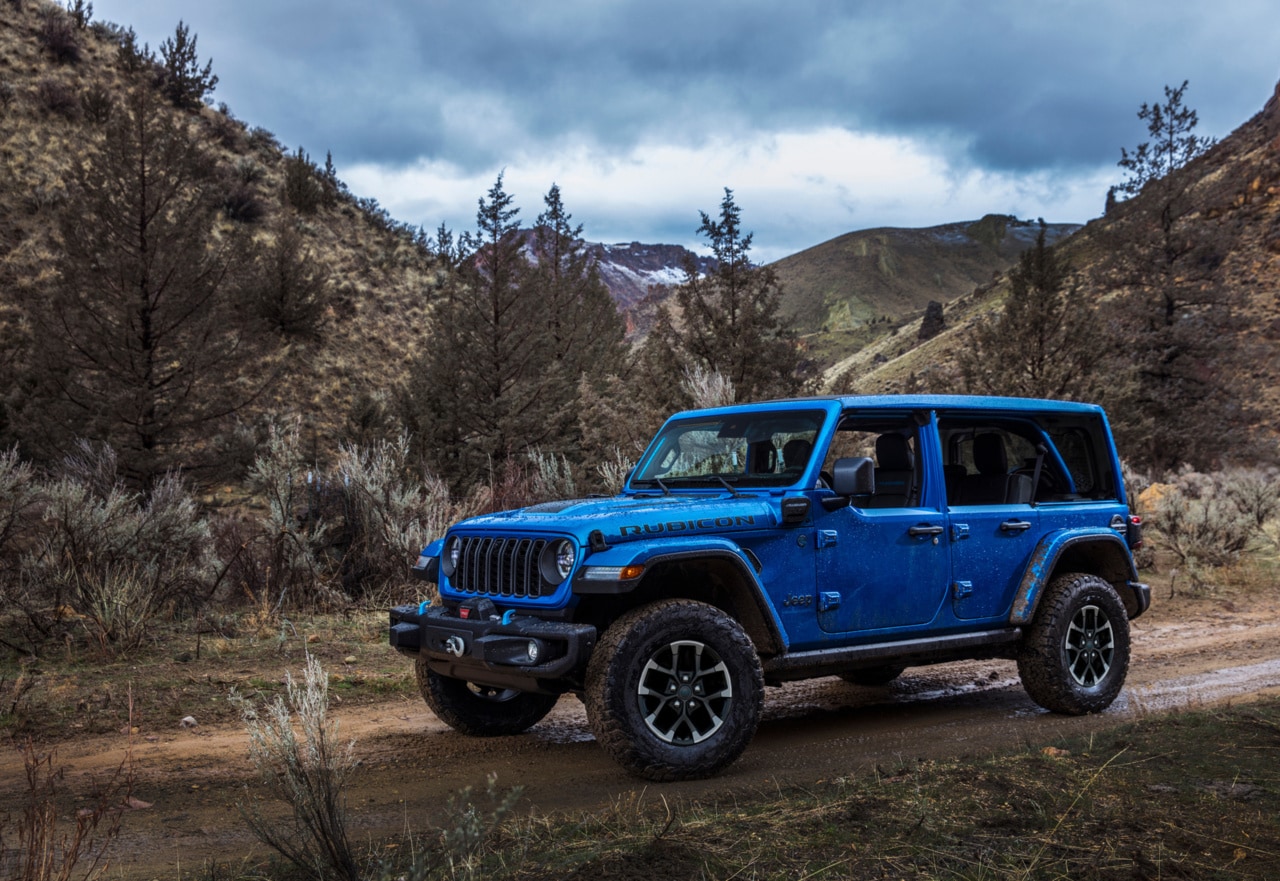 Jeep Wrangler driving on rocky dirt trail through mountains