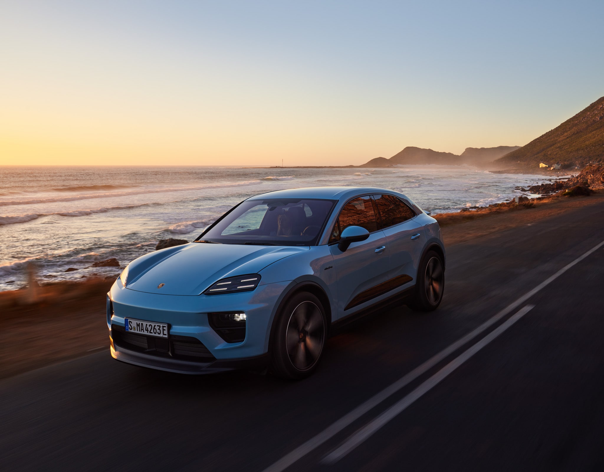 Porsche driving along coast during sunset
