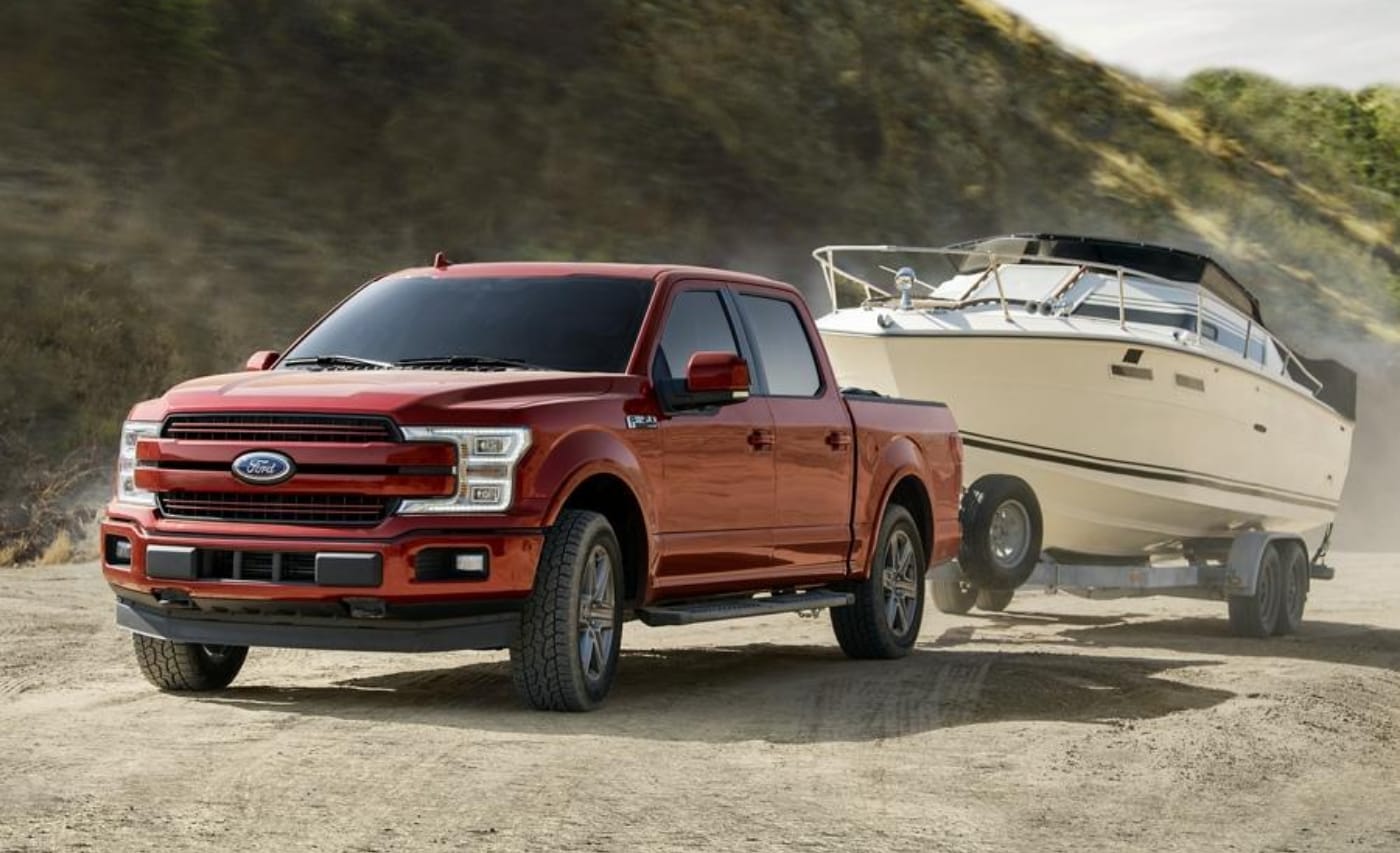 A red 2020 Ford F-150 equipped with the 5.0L V8 engine towing a large white boat