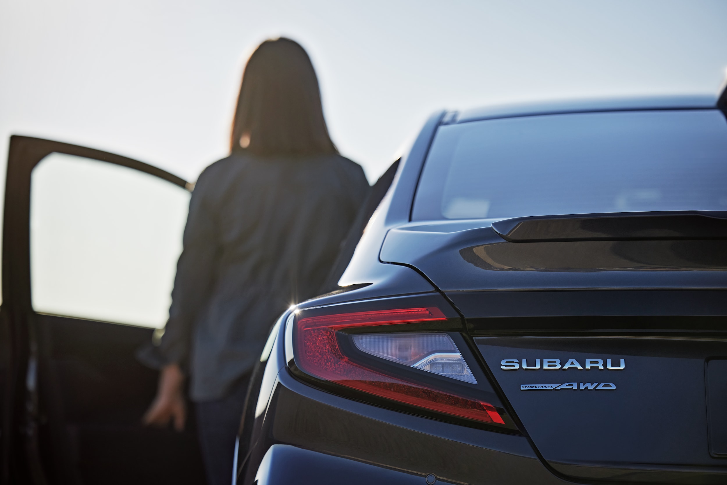 Woman standing next to the driver's side door of a Subaru