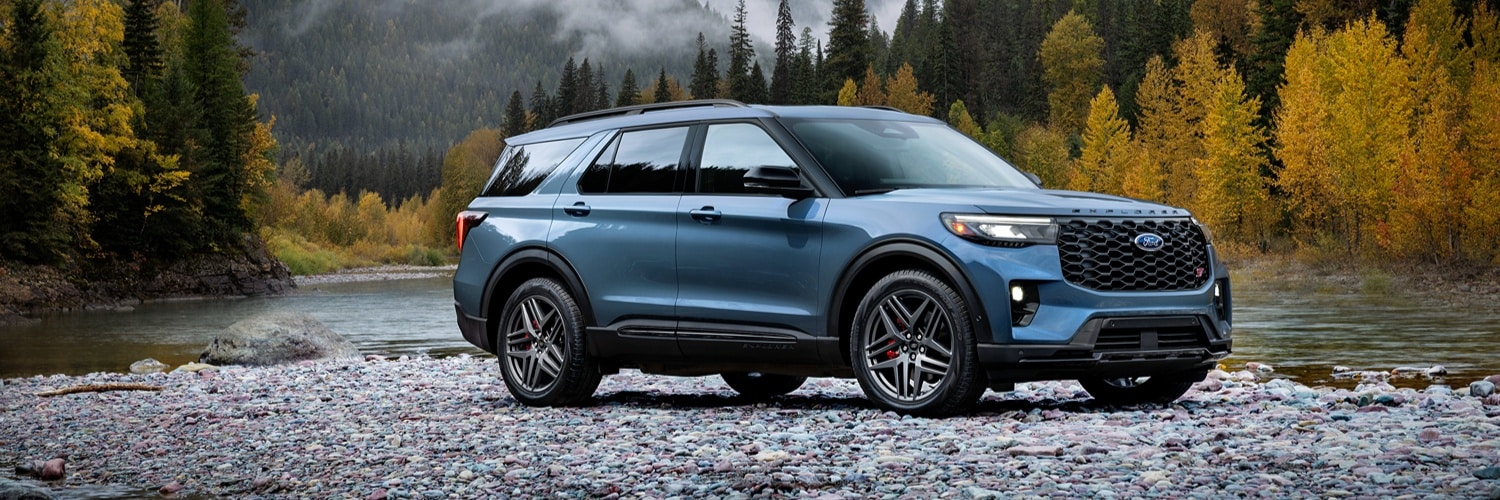 Blue Ford Explorer parked on a rocky bank near mountain