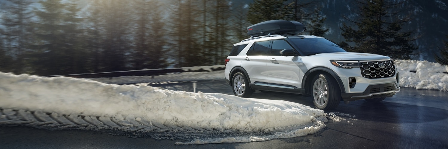 White Ford Explorer climbing a snowy curvy road