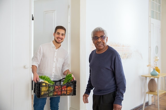 man helping a senior carry his groceries