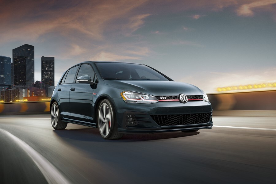 black Volkswagen Golf driving away from a cityscape