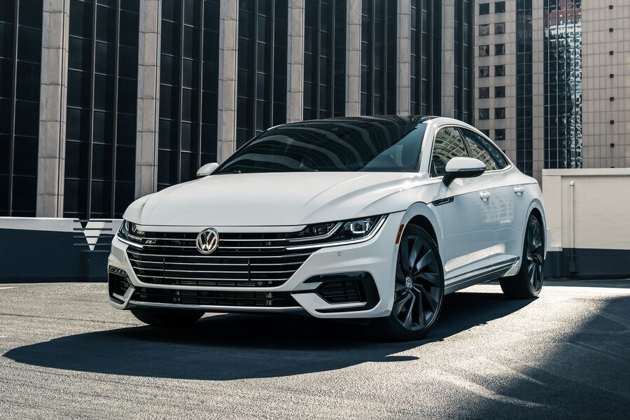 white Volkswagen Arteon parked on the top level of a lot in the middle of a city