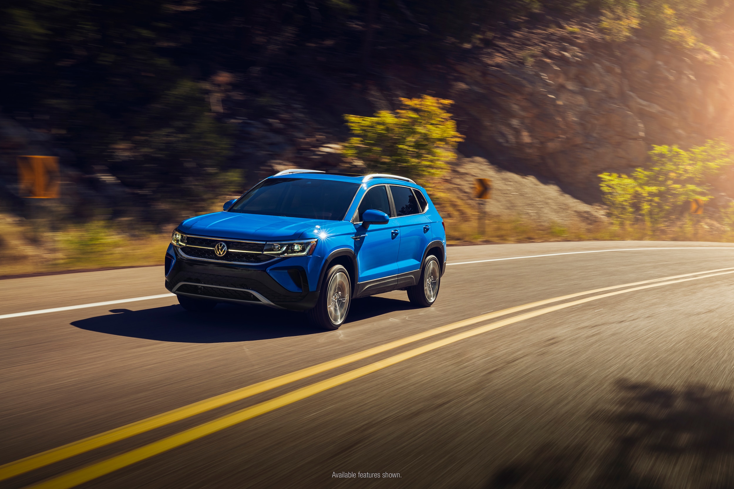 blue Volkswagen Taos driving on a curved road