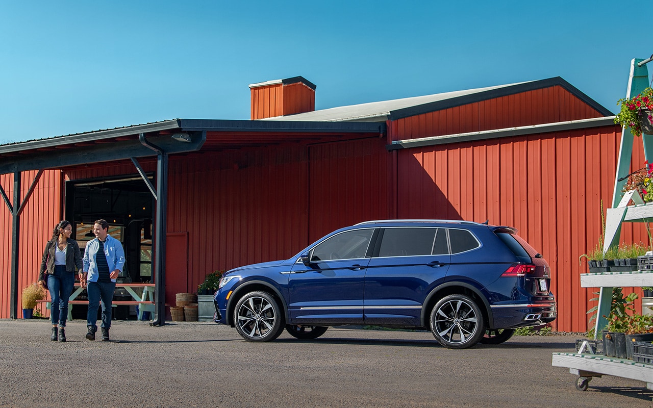 blue Volkswagen Tiguan parked outside a garden center with a couple walking towards it