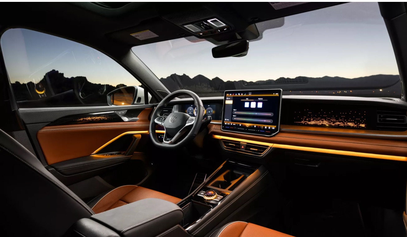 Interior front seat and dashboard view of the 2026 Volkswagen Tiguan in amber brown leather
