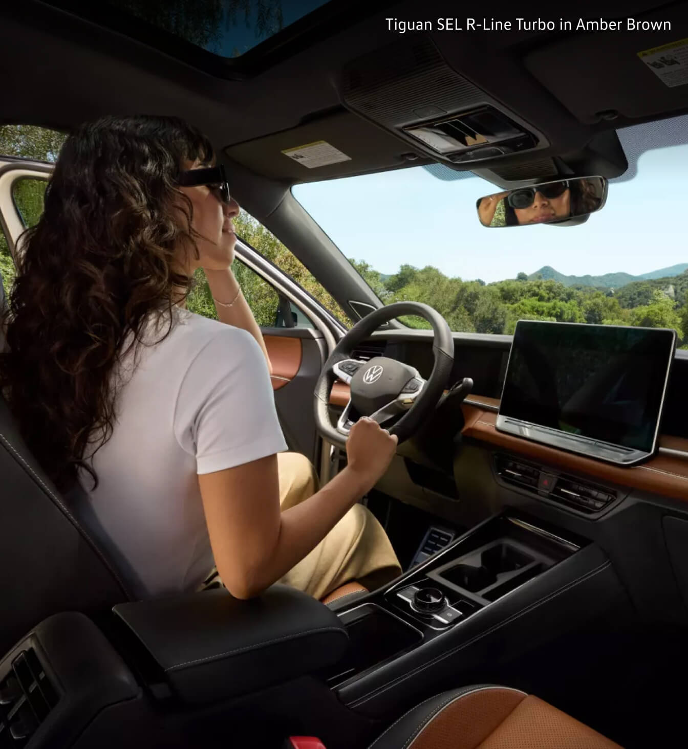 Woman driving her 2026 Volkswagen Tiguan SEL R-Line Turbo with Amber Brown interior features