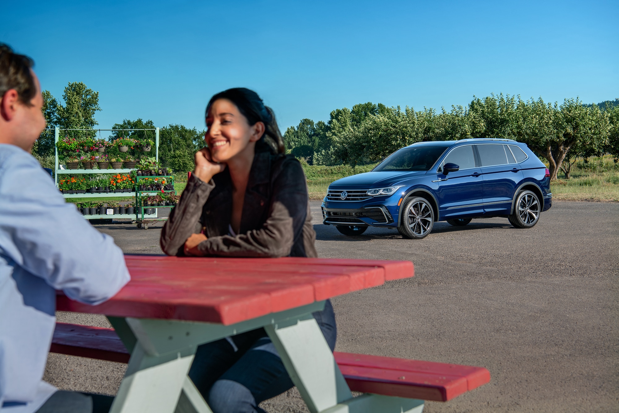 Couple sitting at a picnic table in front of their new 2025 Volkswagen Tiguan