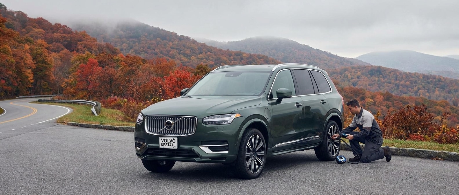 2026 Volvo XC90 on Upstate South Carolina road in fall, technician checking tire pressure with gauge