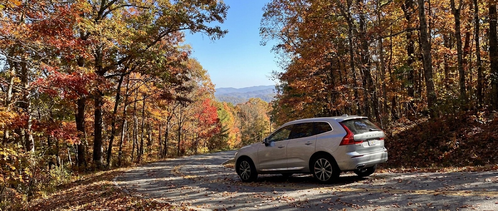 2026 Volvo XC60 descending a steep Blue Ridge foothills road near Greenville, SC in autumn