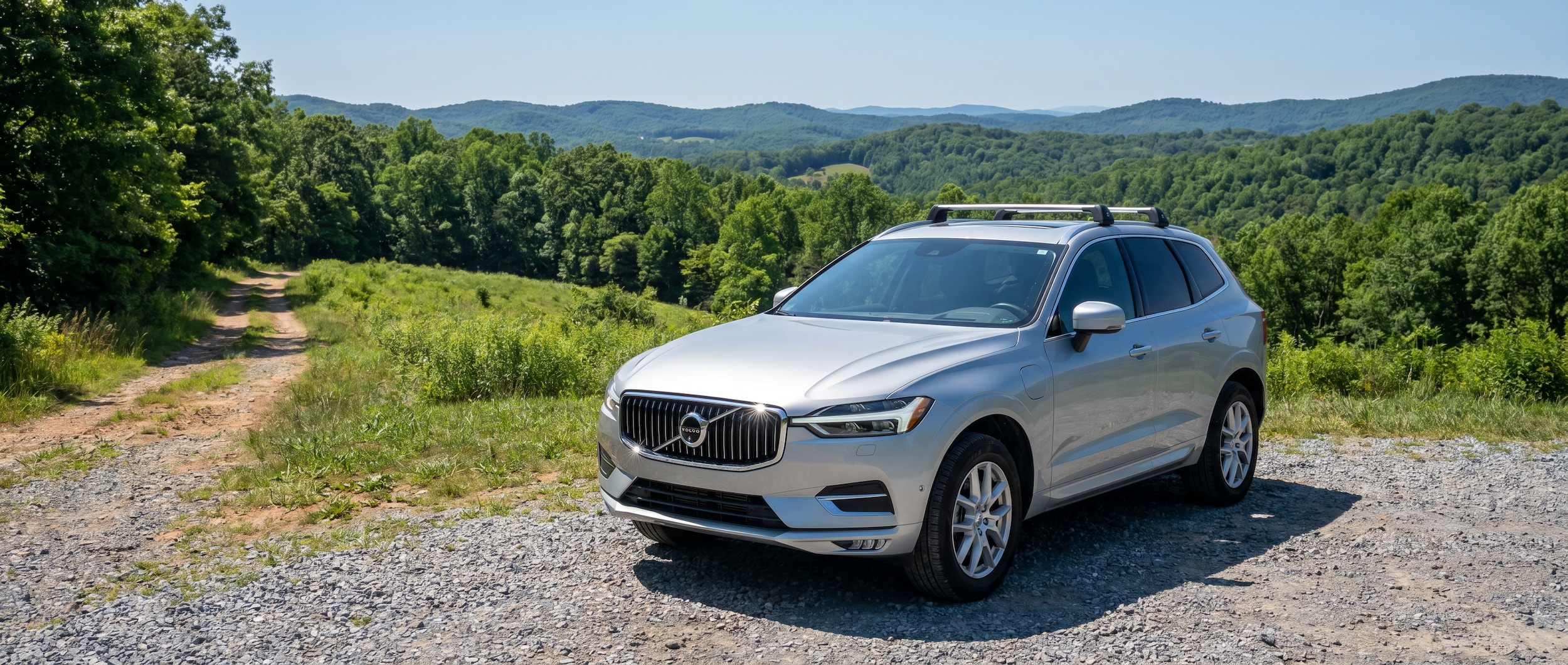 2026 Volvo XC60 plug-in hybrid parked in Upstate South Carolina summer landscape with Blue Ridge foothills in background