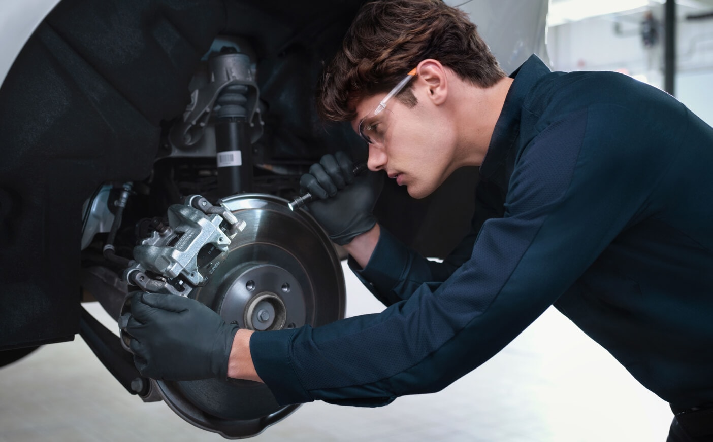 A Volvo Certified Technician inspects the brake pads on a Volvo car's rotor.