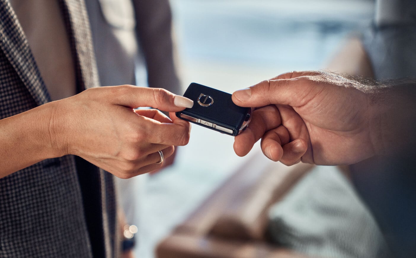 A close-up shot of two hands exchanging a Volvo key fob.