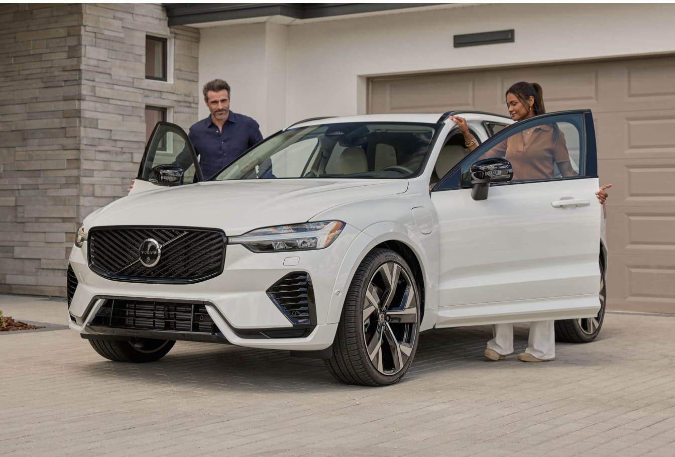 Couple standing beside a white Volvo XC60 parked in a residential driveway.