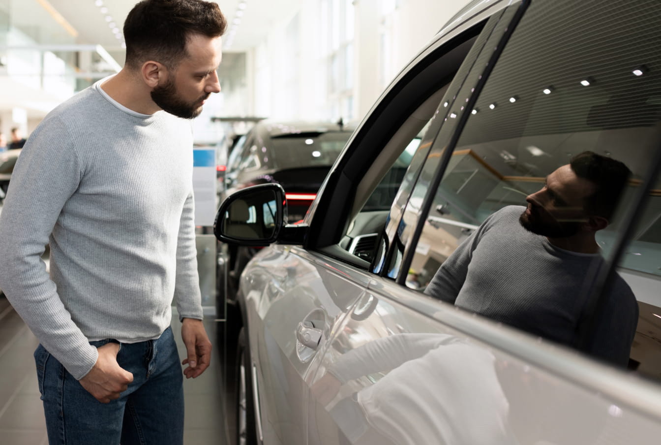 Customer inspecting a vehicle at a dealership showroom.